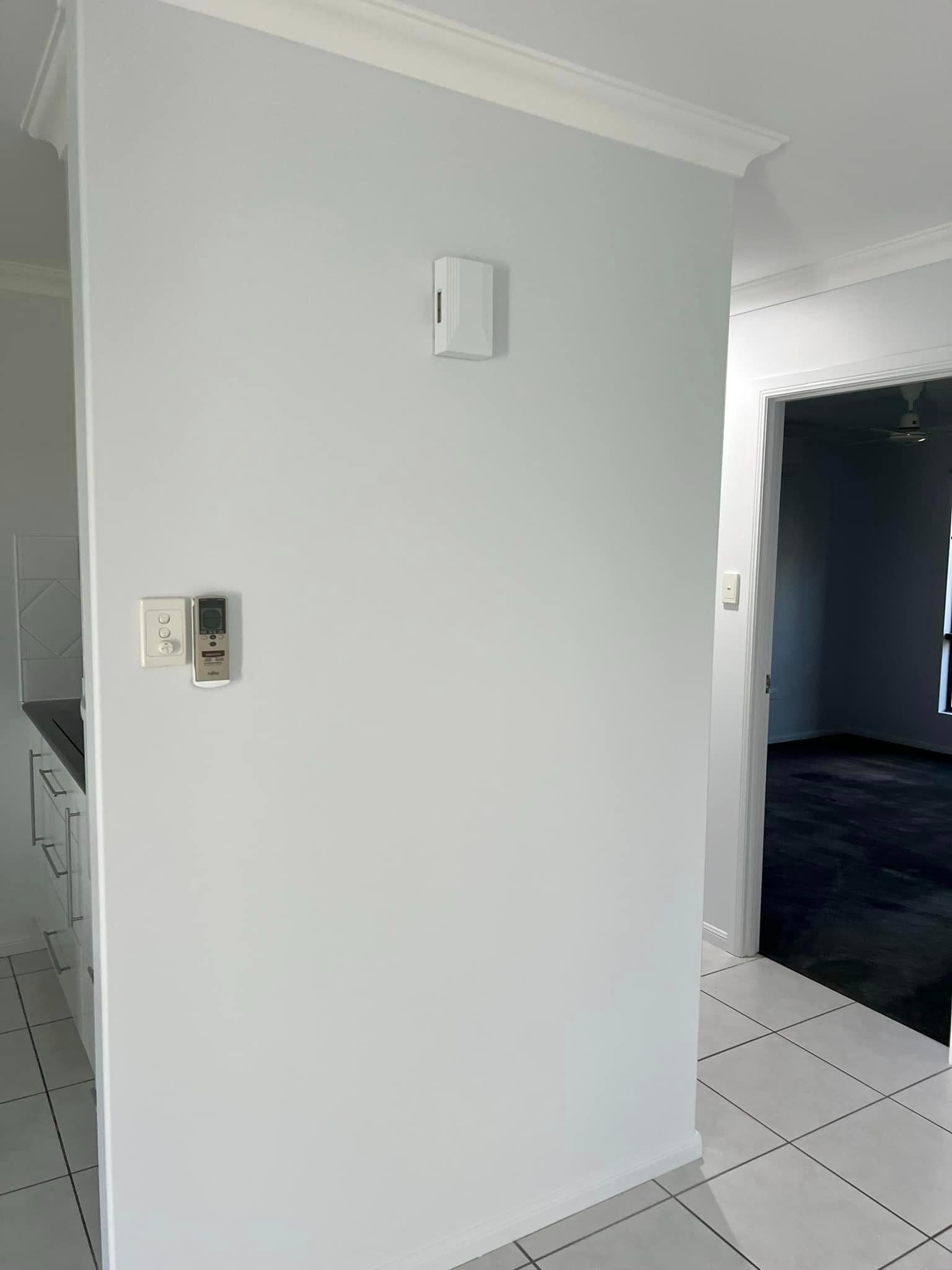 A white wall in a room with a thermostat on it.