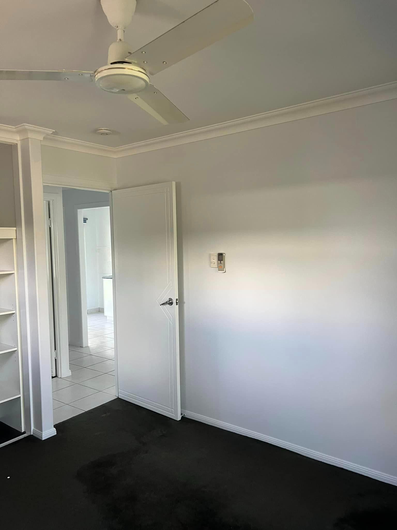 An Empty Room with A Ceiling Fan and A Door — Darren Smith Painting Pty Ltd in Sarina, QLD