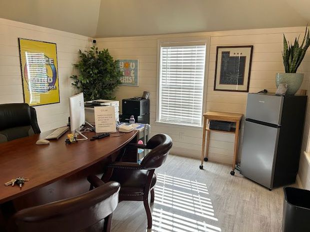 Small office with desk, chair, file cabinet, window blinds, and sunlight casting stripes on the floor.