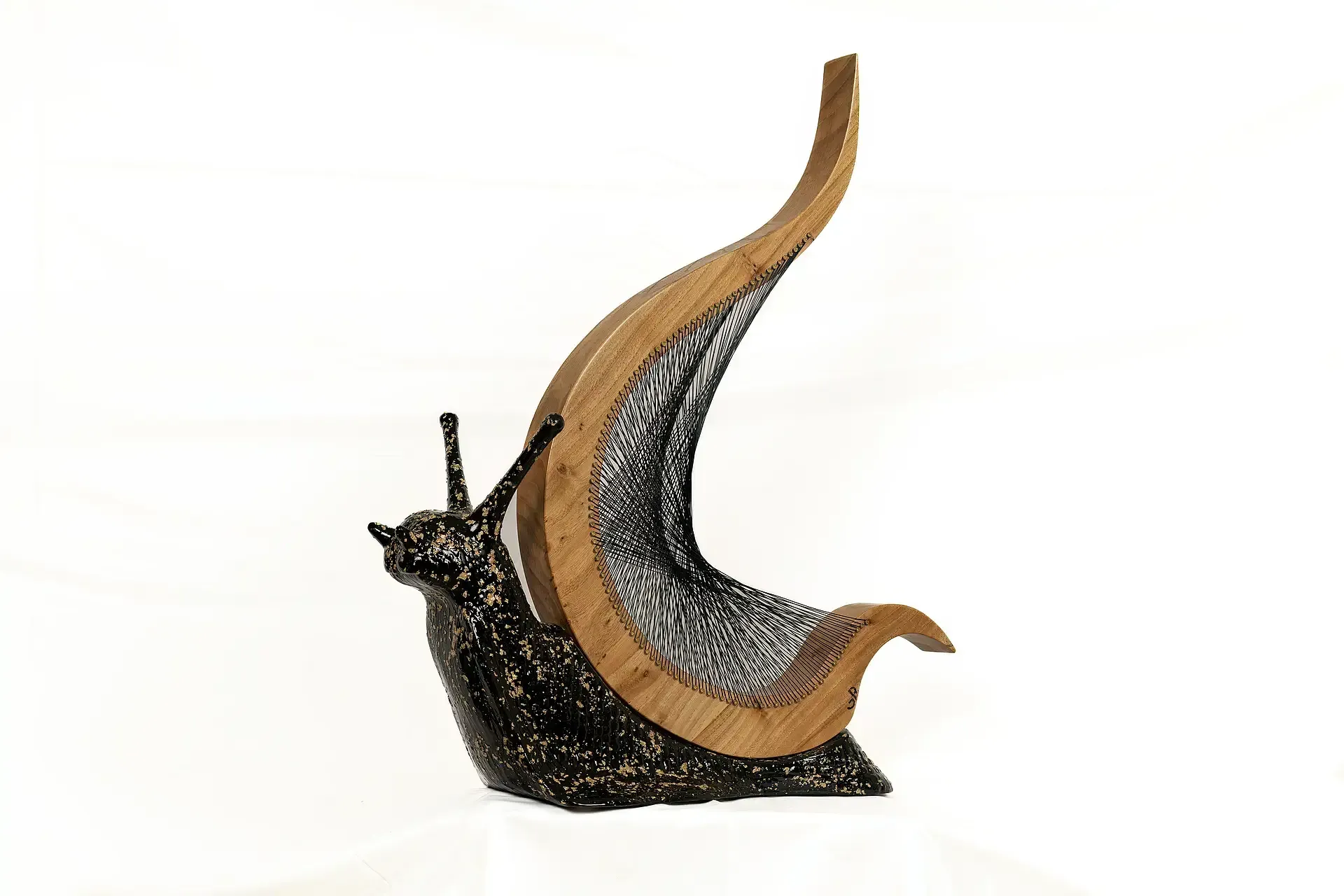 Scultura di chiocciola con corpo scultoreo in resina scura e screziata color oro, guscio aperto e sinuoso realizzato in legno chiaro naturale con fili metallici di acciaio. Opera materica dell'artigiano-artista Guerino Rusconi.