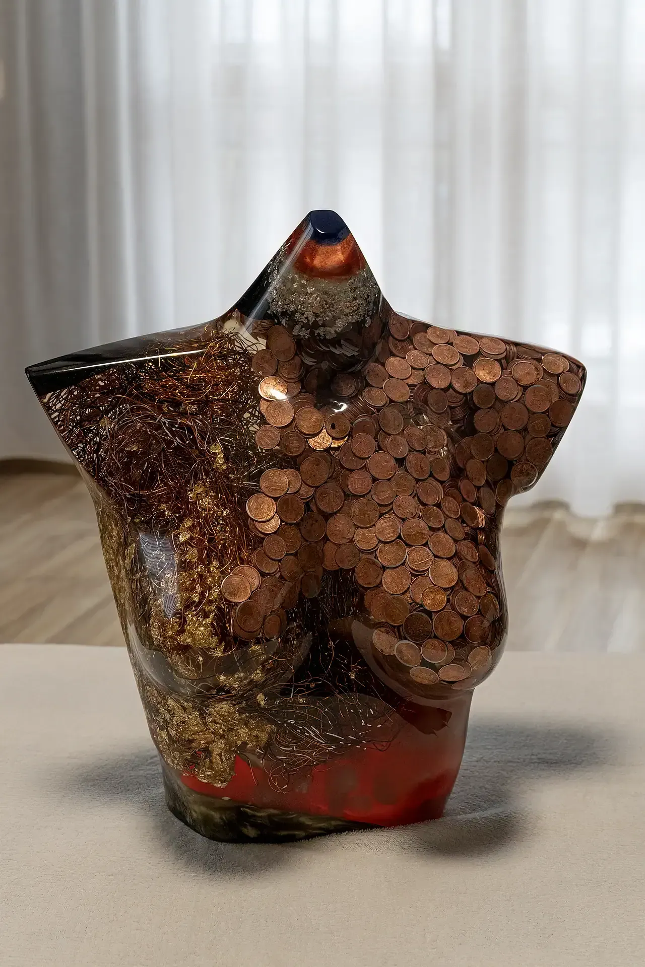 Scultura in resina epossidica, fili di alluminio, foglia oro e monete color rame, raffigurante un torso femminile. Inquadreatura frontale. Opera di Guerino Rusconi