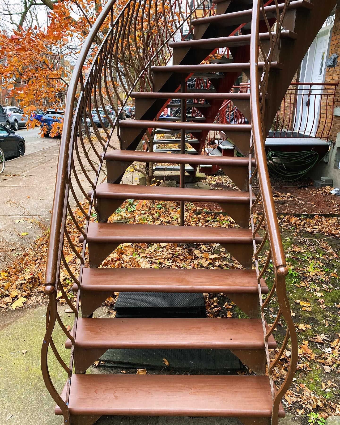 Rusty spiral staircase with open metal steps outdoors amid autumn leaves and trees
