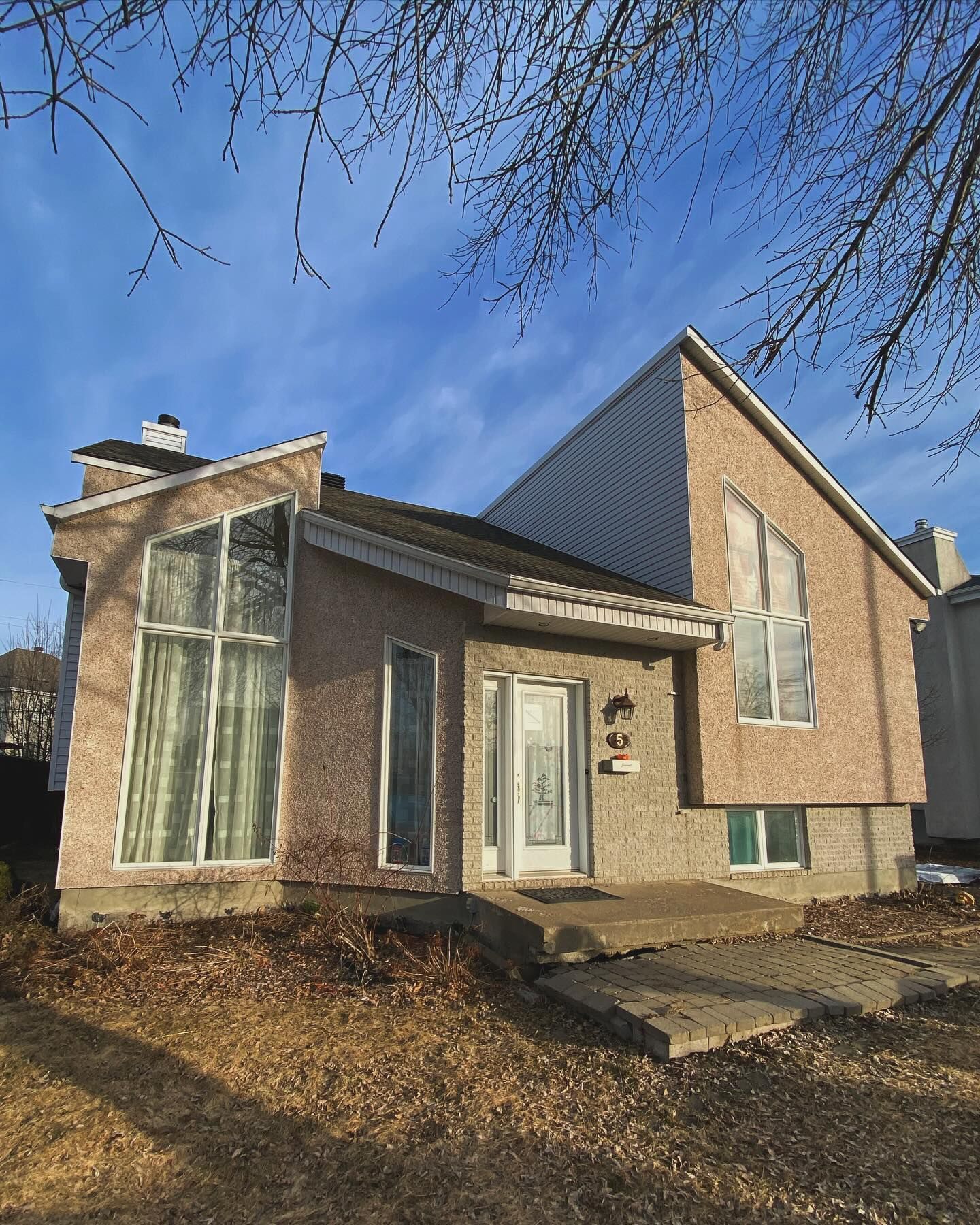 Modern brick house with large windows and a white front door on a sunny day