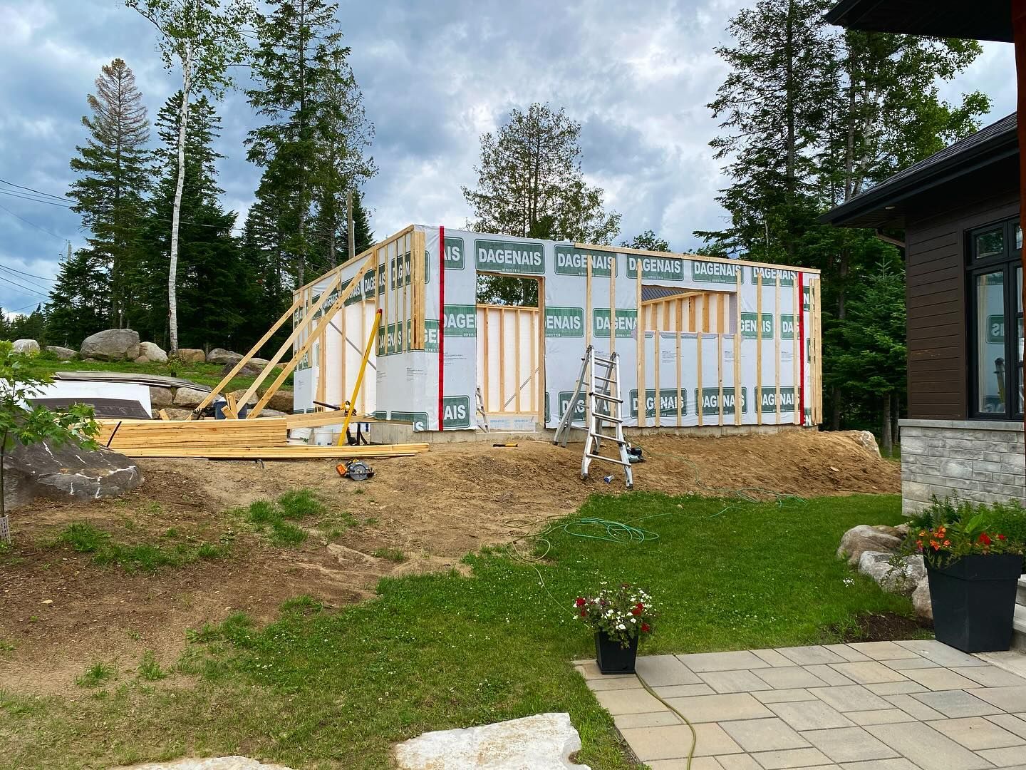 Partially framed house exterior with ladder, insulation, and construction materials in a yard
