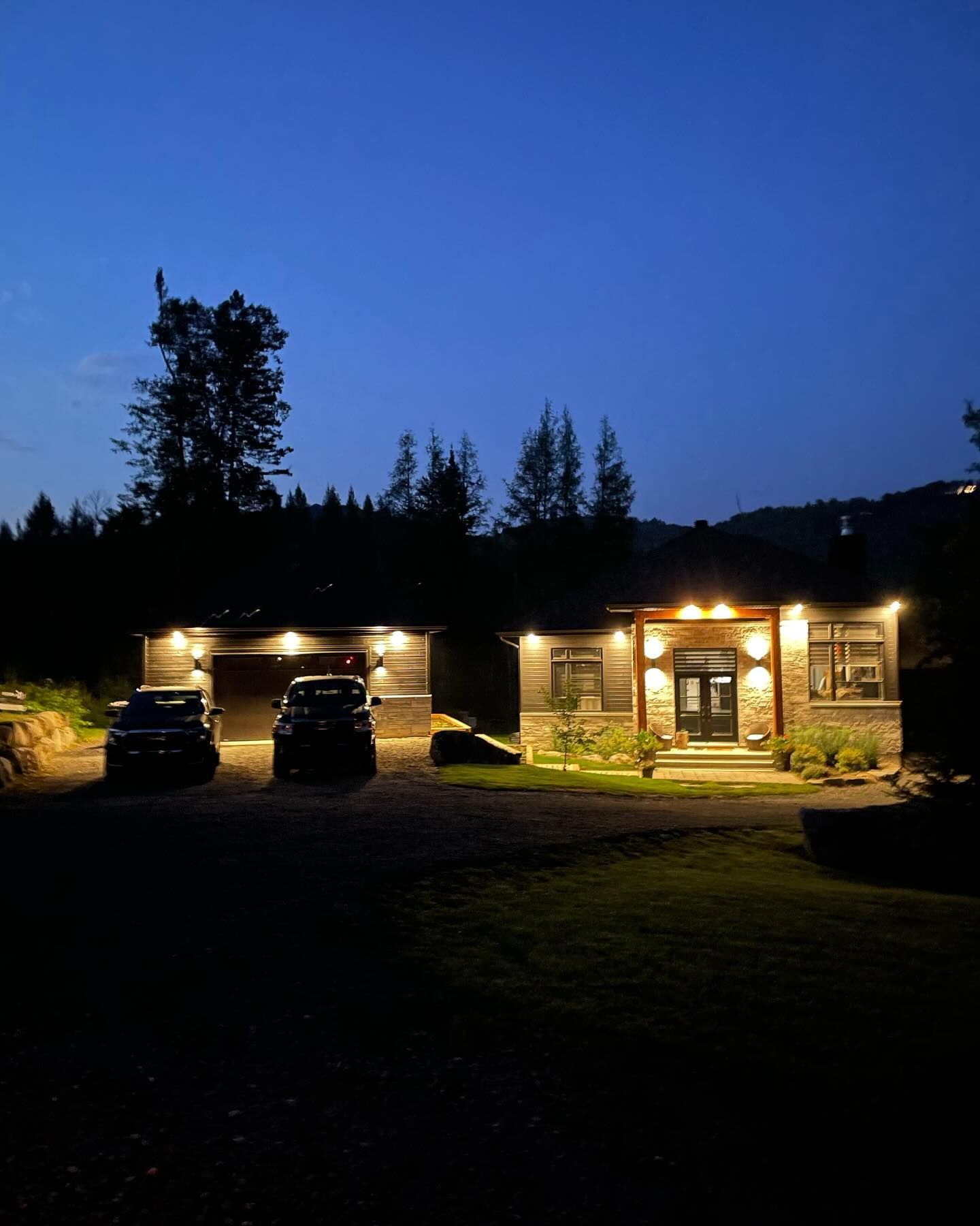 Nighttime house and garage with warm lights glowing against a deep blue sky.