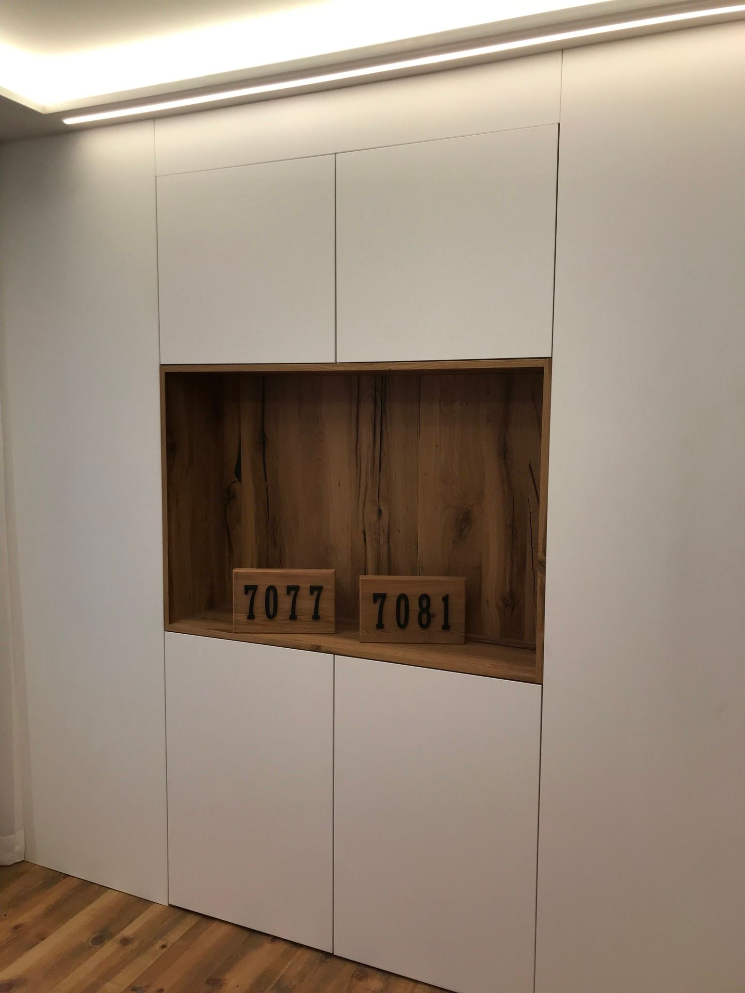 Built-in white cabinet with open wood niche and two numbered boxes inside