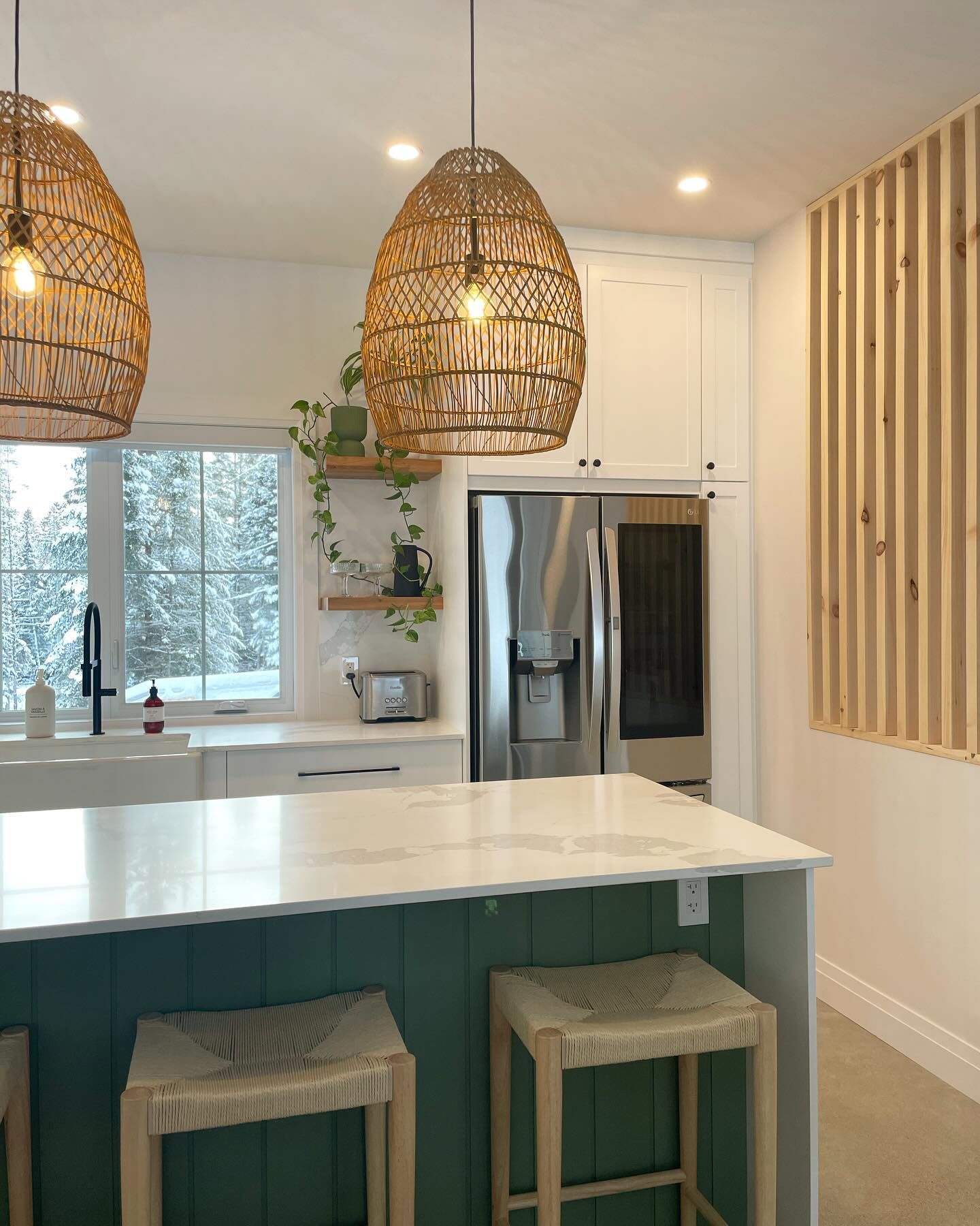 Modern kitchen with teal island, wicker pendant lights, stainless fridge, and vertical wood slat accent wall