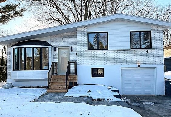 Snowy suburban house with white siding, front steps, and an attached garage