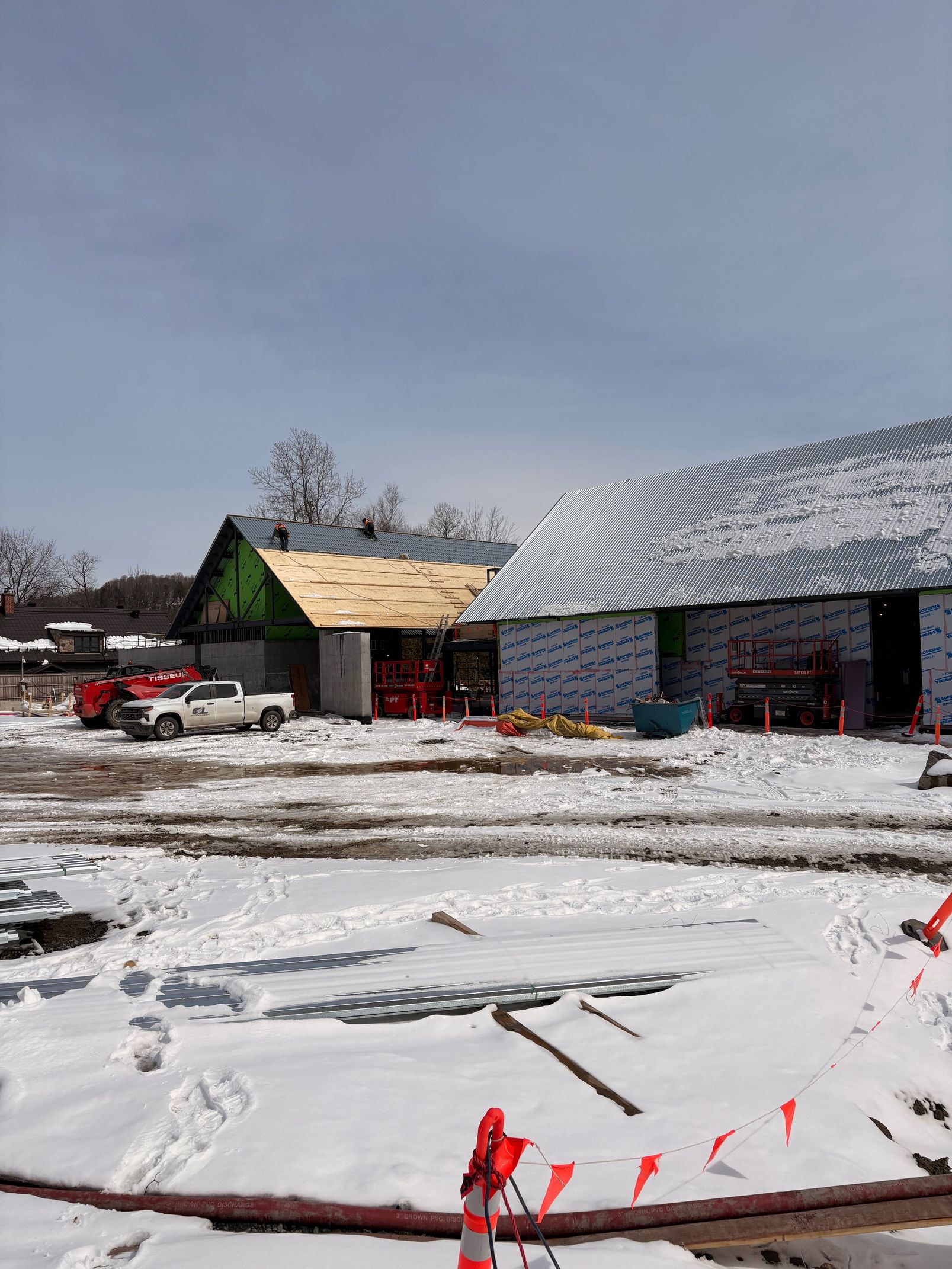 Snowy rural scene with houses, a red vehicle, and red flags in the foreground