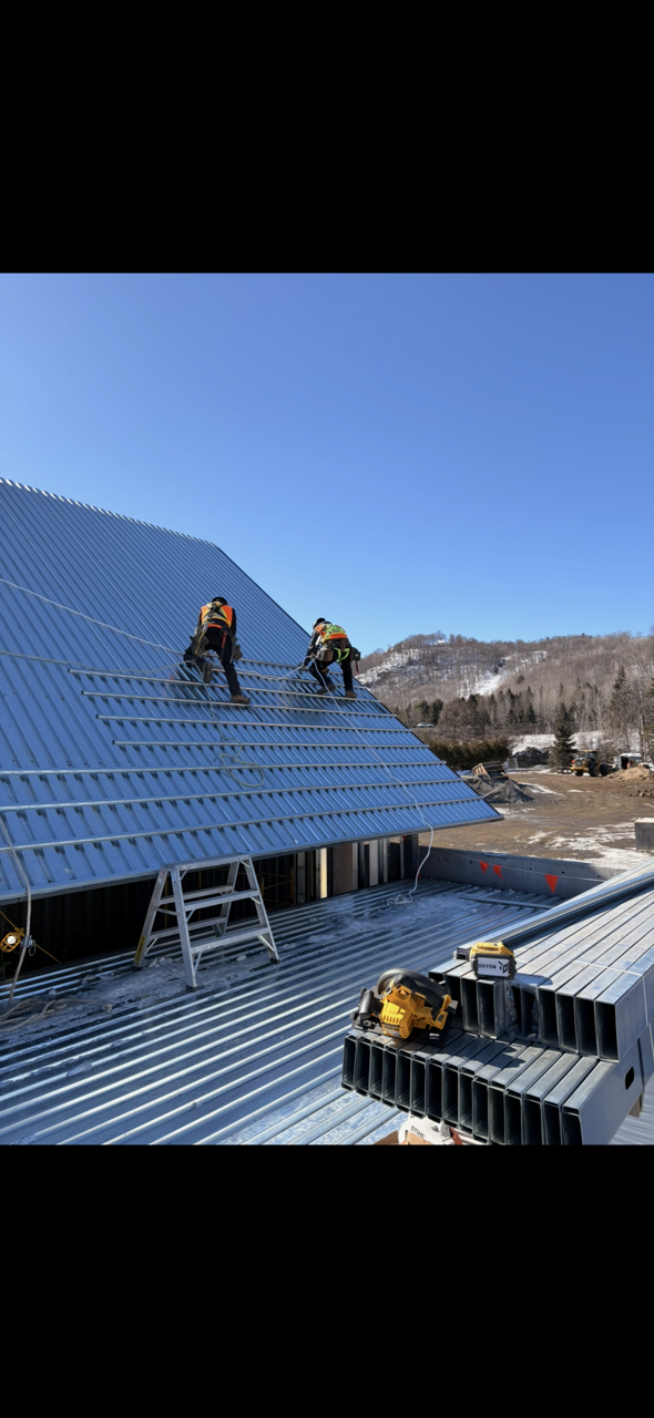 Two workers on a blue roof installing panels on a sunny day
