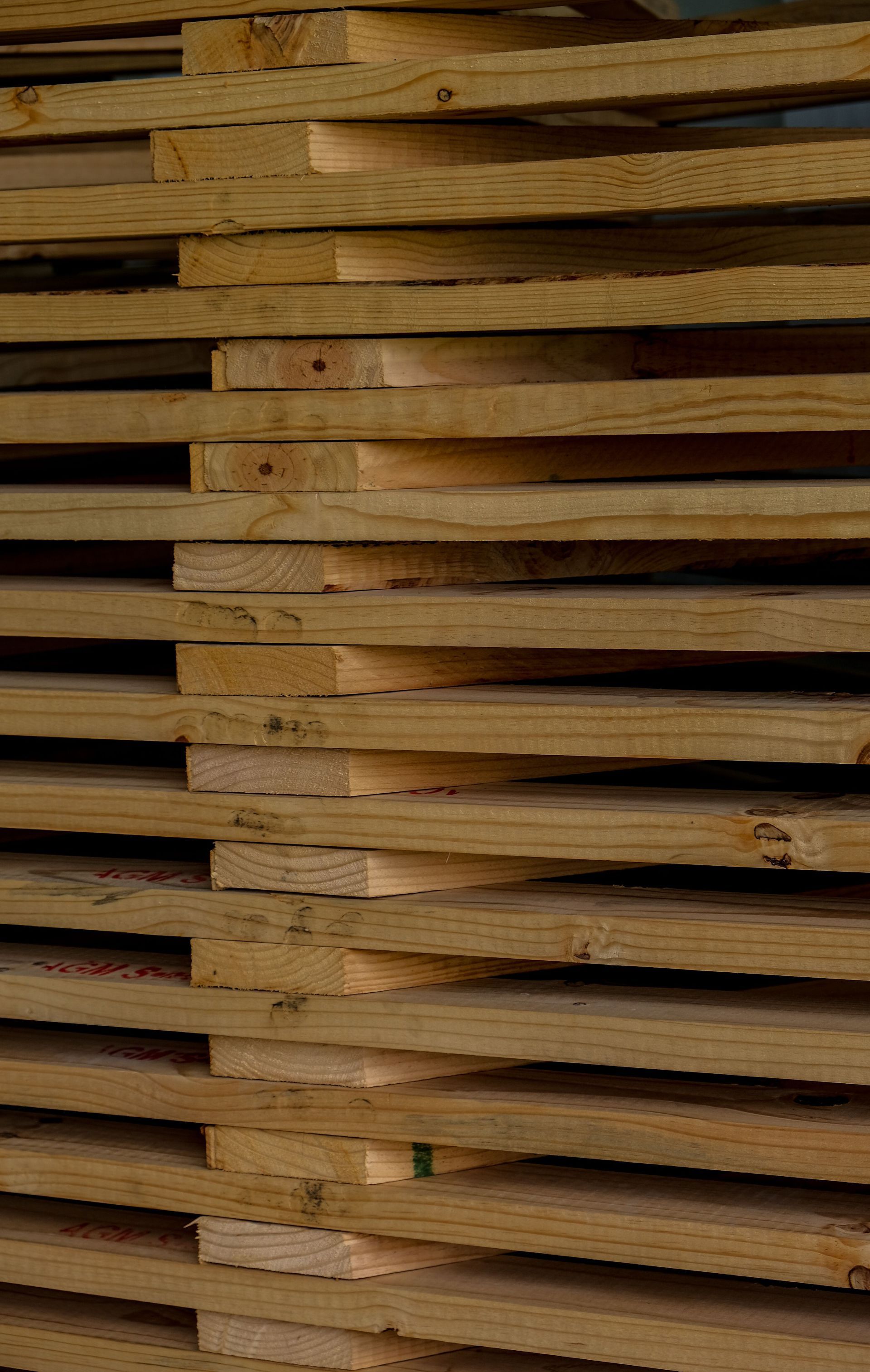 Stacked wooden planks in a close-up view, showing layered tan and brown boards.