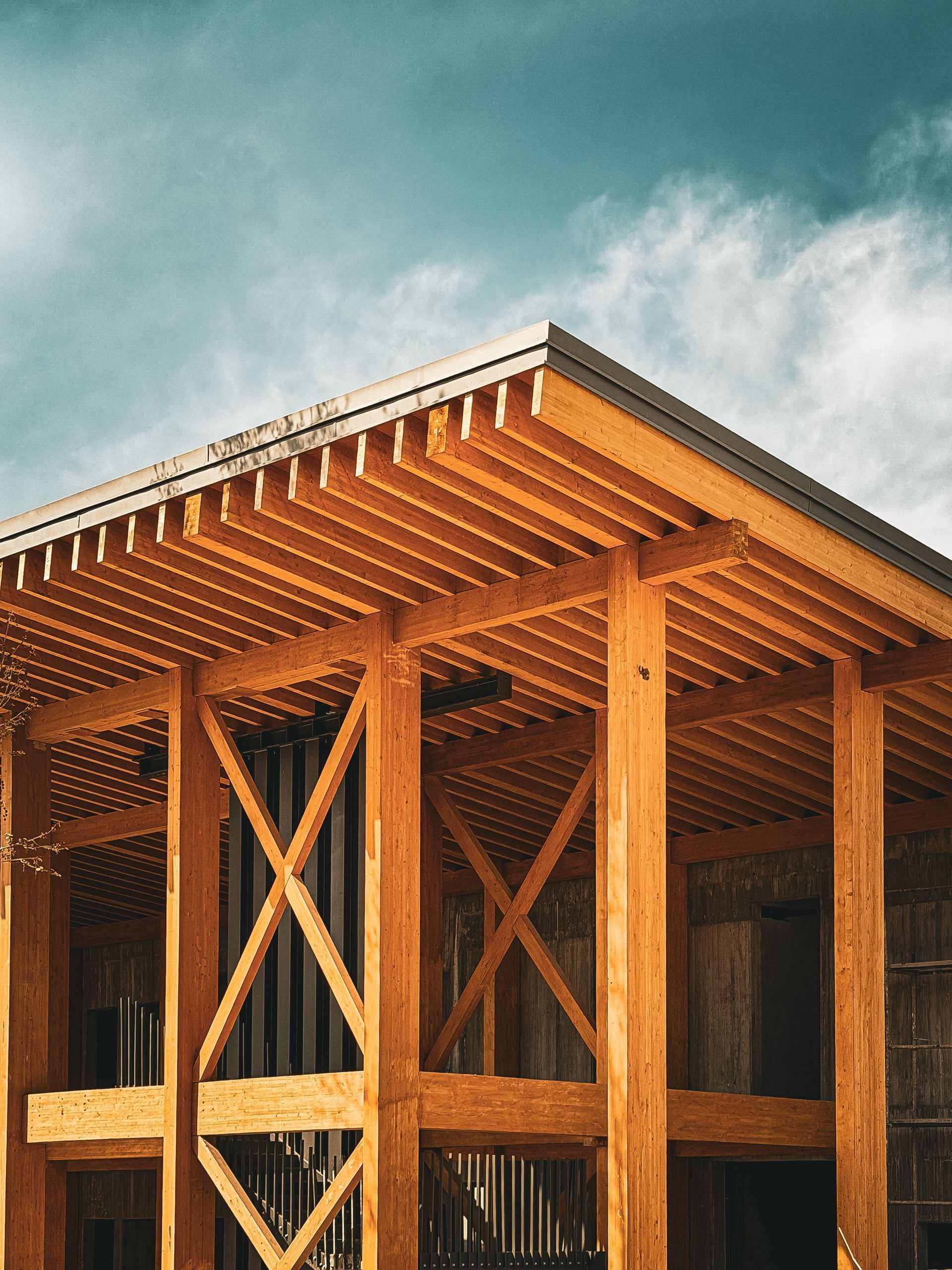 Wooden timber-framed building under construction against a blue sky