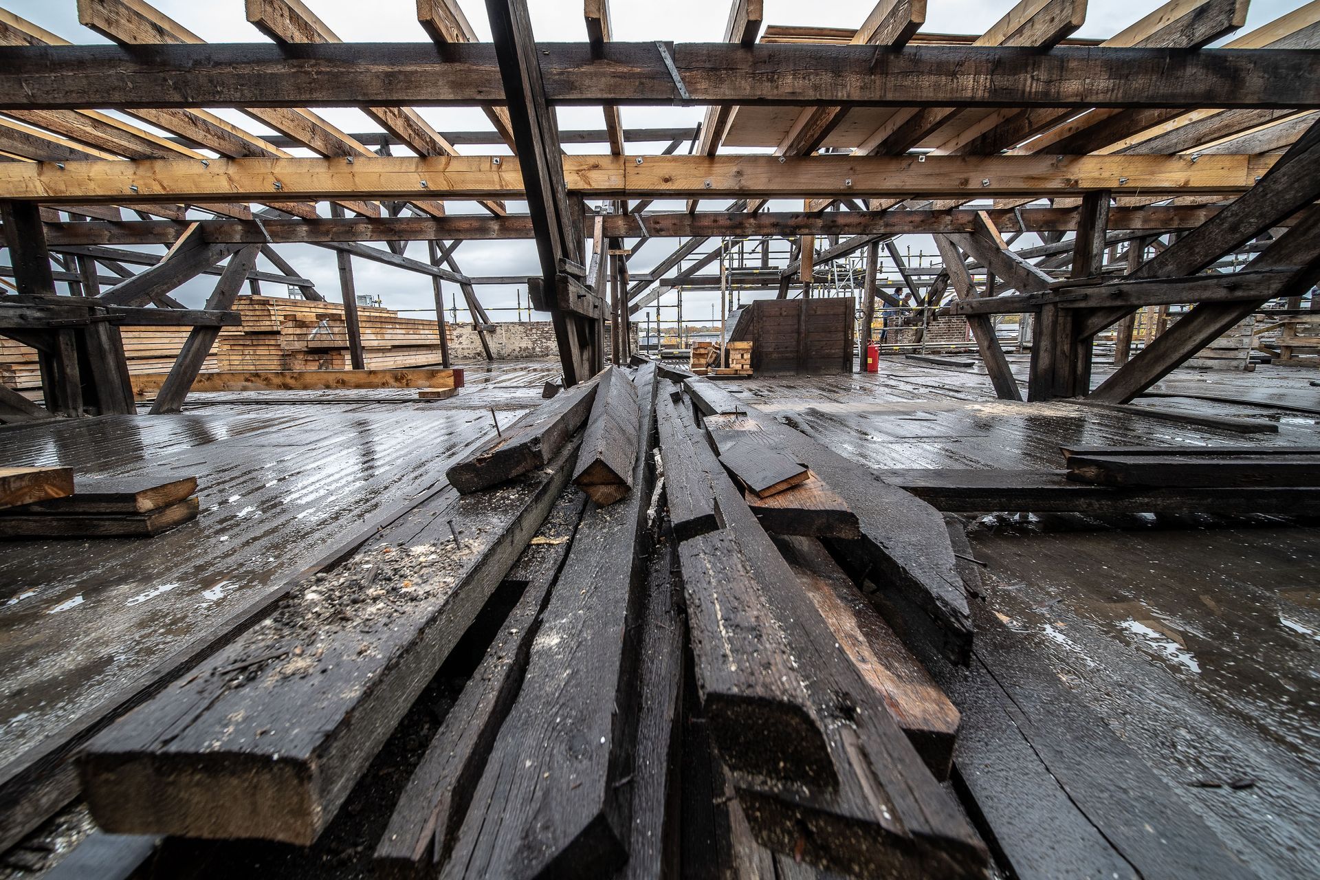 Damaged roof interior with exposed wooden beams and debris after fire or storm damage