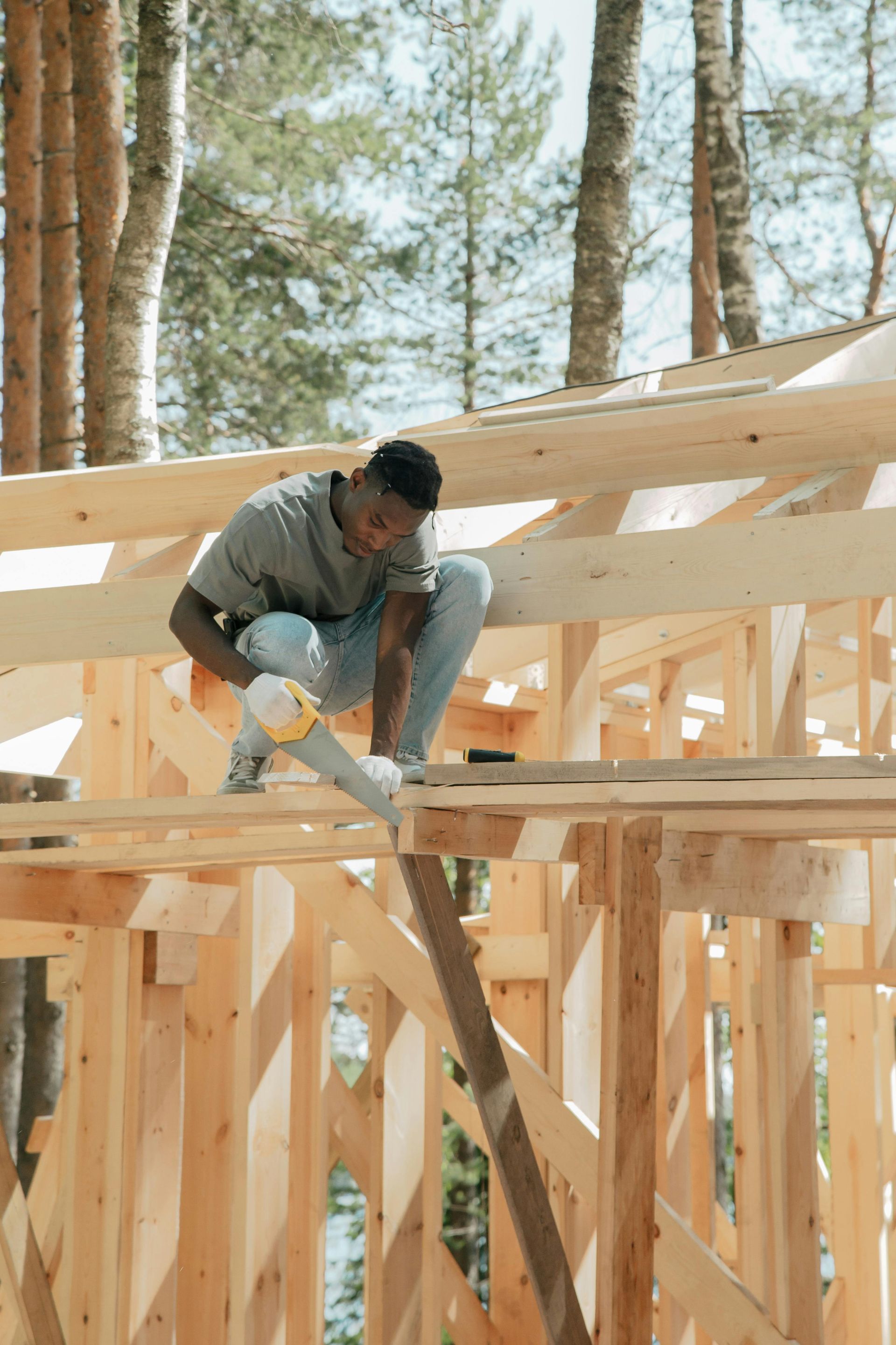 Worker installing wooden roof framing on a house under construction outdoors