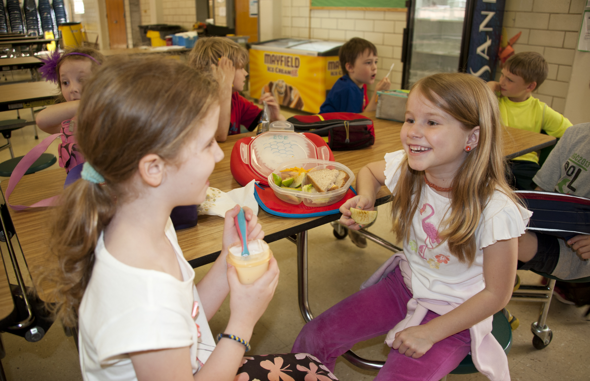 A group of young girls are sitting at a table eating food.