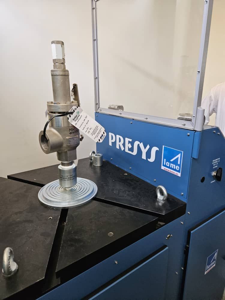 Une valve est posée sur une table à côté d'une machine sur laquelle est écrit presys.