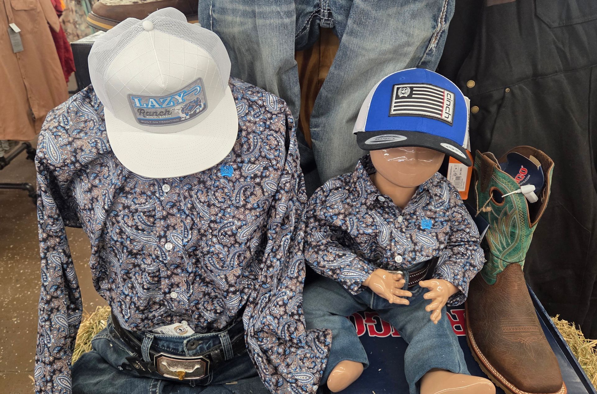 Two people in matching patterned shirts and caps stand in a clothing store display.