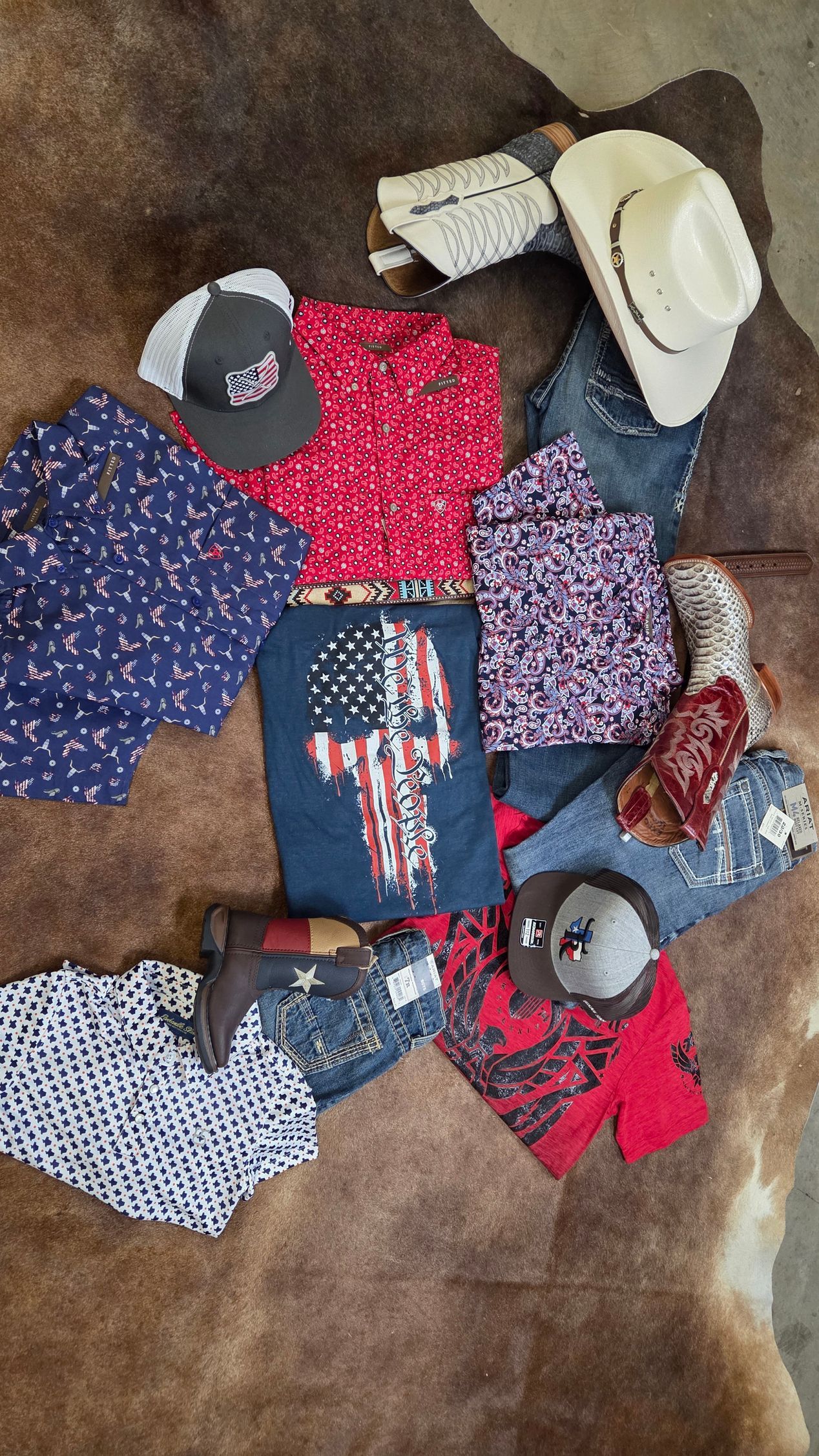 Assorted folded shirts, tops, and hats laid out on a brown floor.