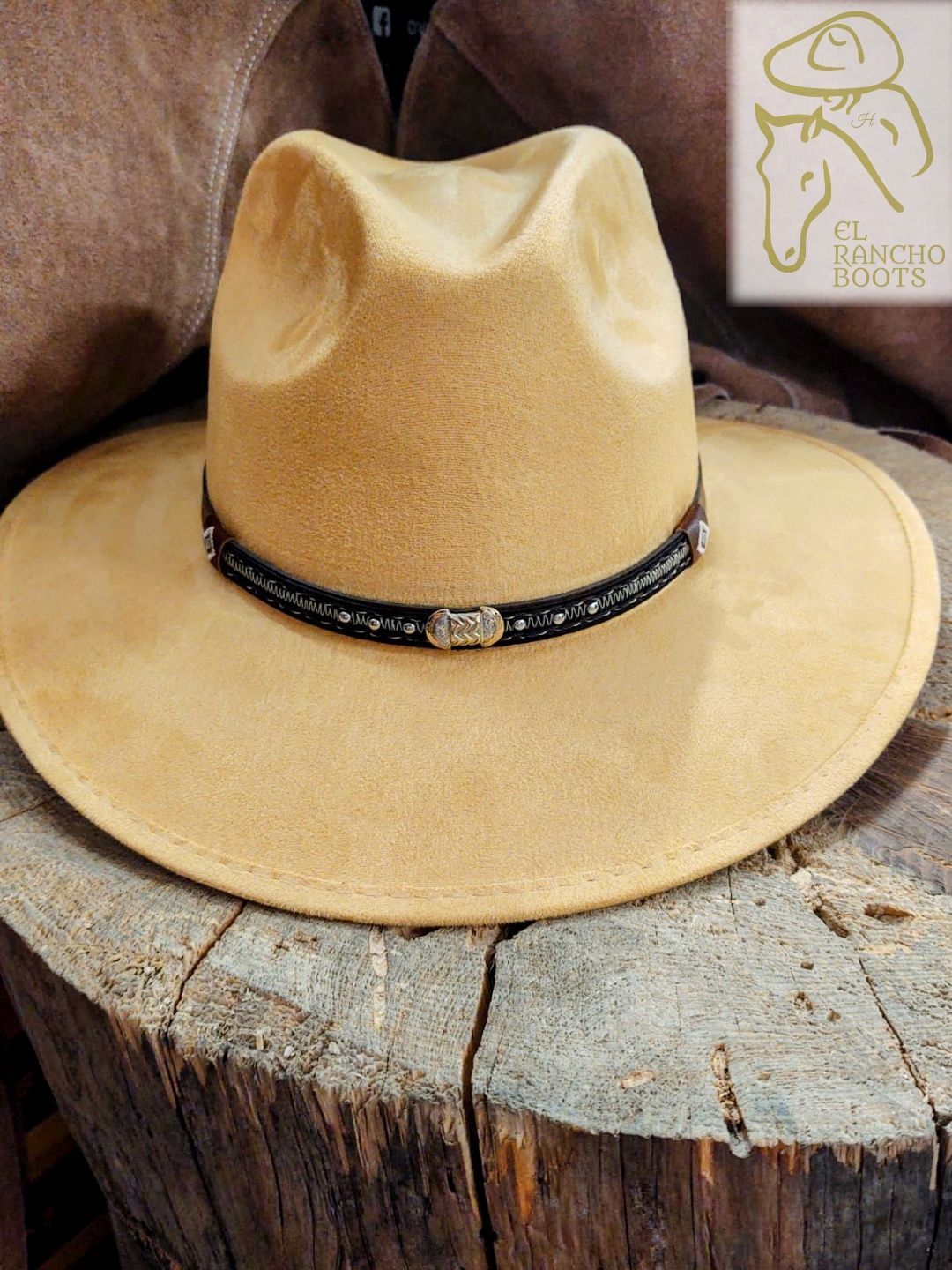 Tan cowboy hat with black band resting on a cut tree stump