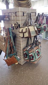 Handbags and purses hanging on a brick display rack in a retail store