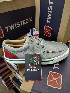 Gray Twisted X sneaker on branded boxes, with tags and tan lining displayed in store