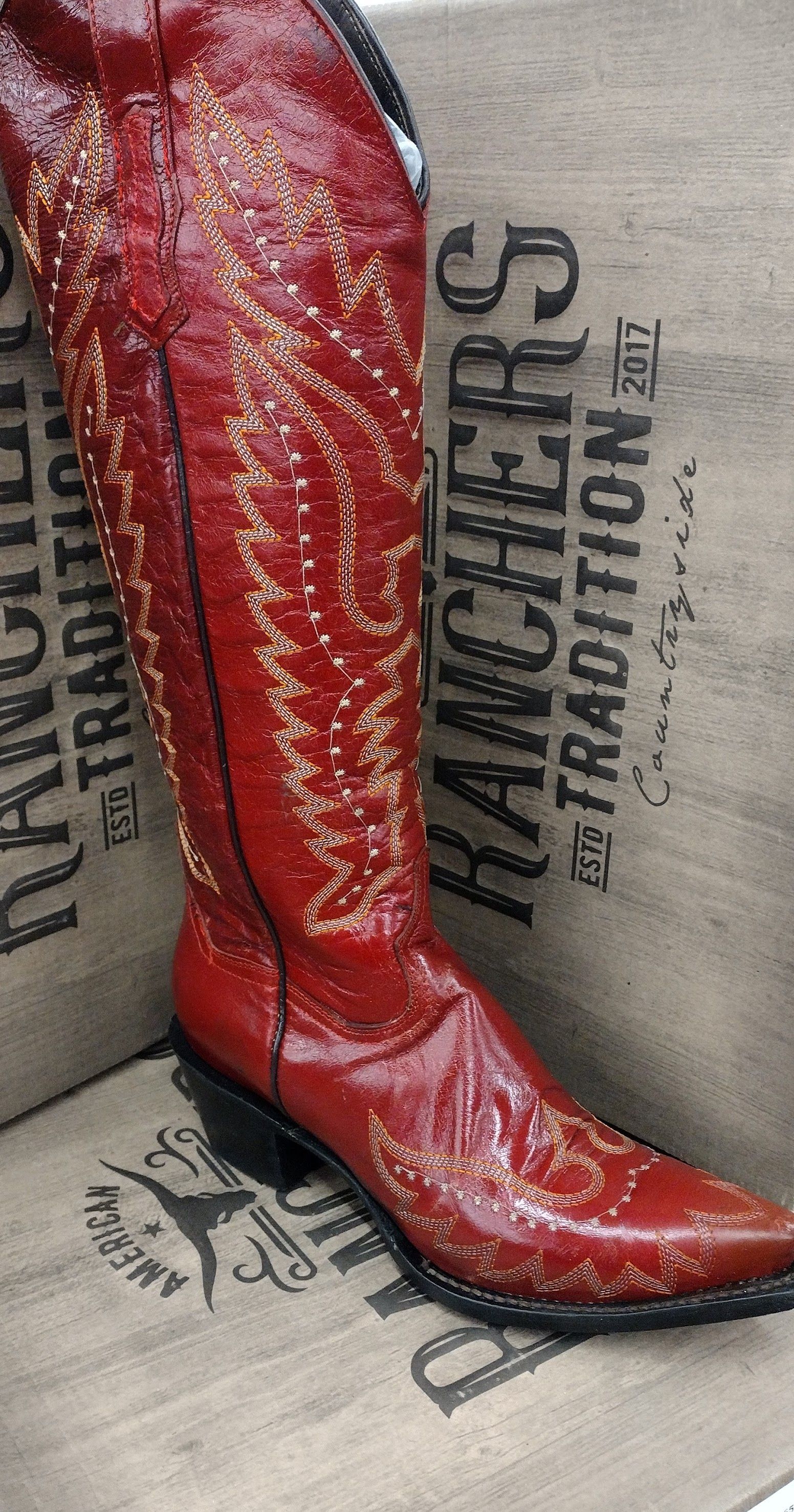 Red sequined knee-high boot on a beige Hancher's Foundation backdrop