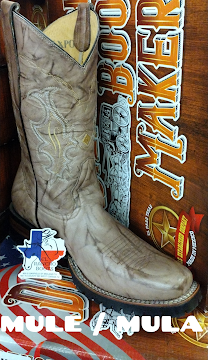Tan cowboy boot with embroidered stitching beside a boot box labeled 