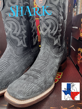 Gray cowboy boots with embroidered flames on a store shelf, with a turquoise “SHARK” label above.