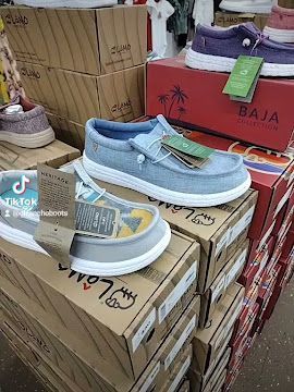 Blue sneakers on stacked cardboard boxes in a store display, with a red Baja box nearby.