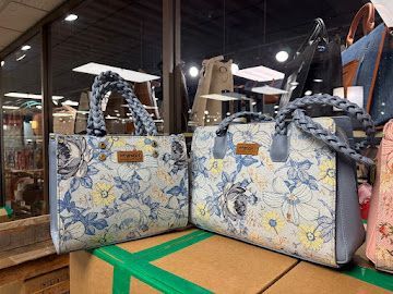Two floral tote bags with braided handles displayed on a store counter