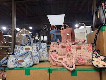 Floral handbags in blue, pink, and tan displayed on a store shelf under bright lights