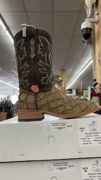 Cowboy boot on a display box in a store, with brown and black embroidered leather design.