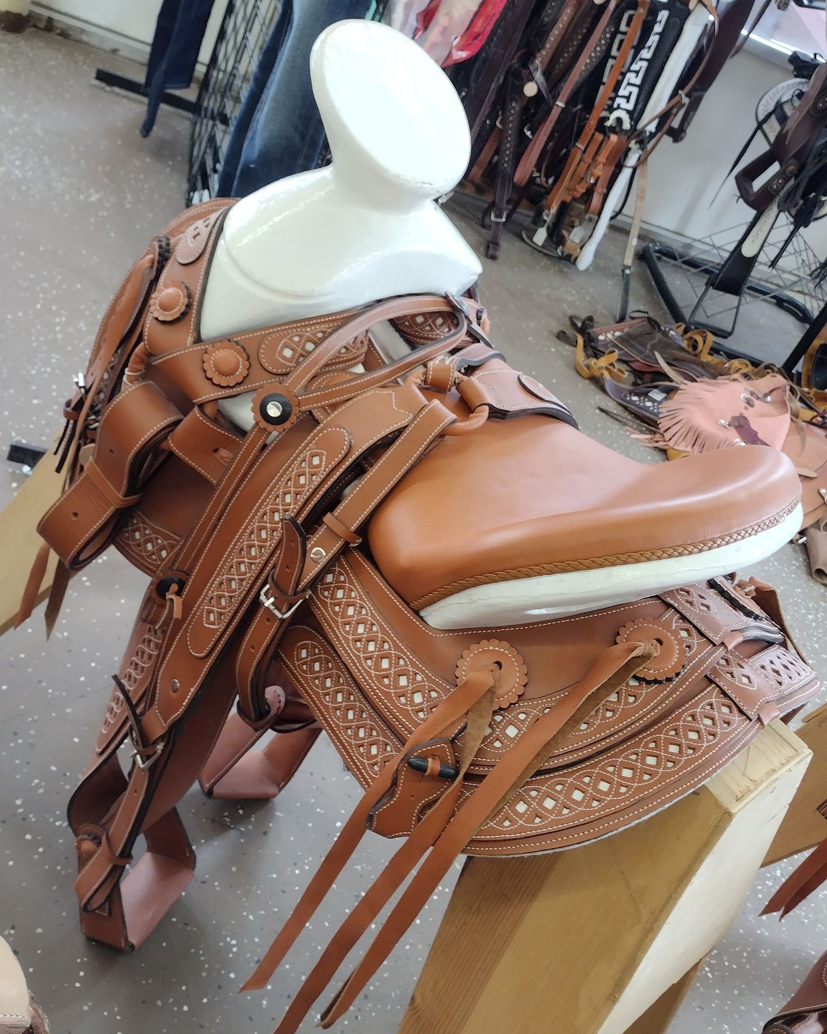 Brown leather fringed saddle on a stand in a shop display