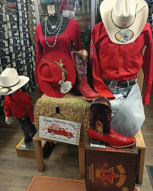 Red cowboy-themed mannequin display with hats, boots, and denim outfit in a store