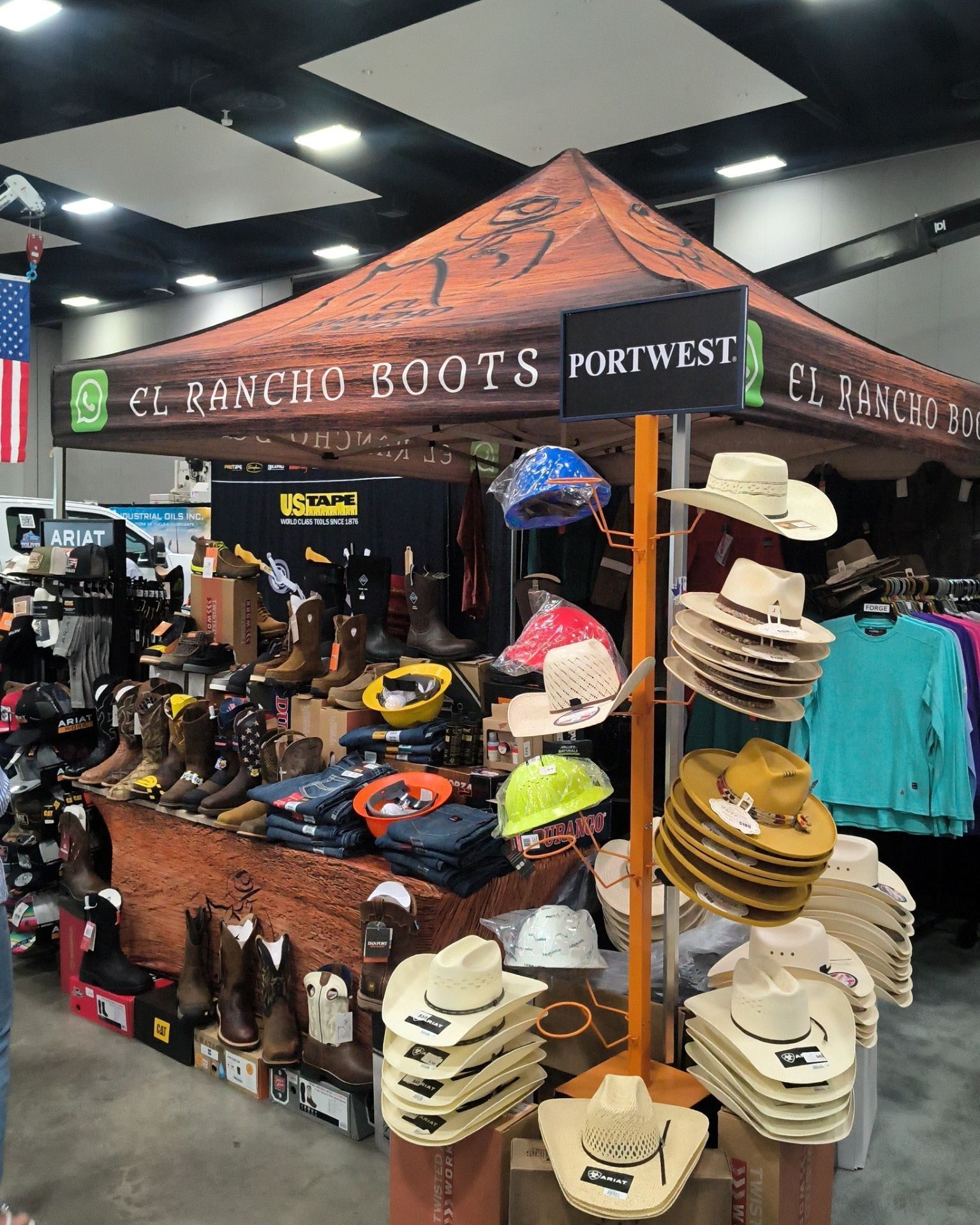 Western boot and hat booth with colorful boots, belts, and straw hats at an indoor market.