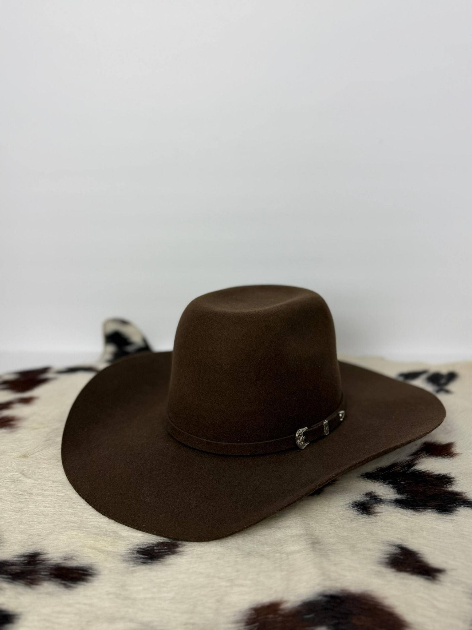 Brown cowboy hat on a white-and-black patterned blanket against a light background