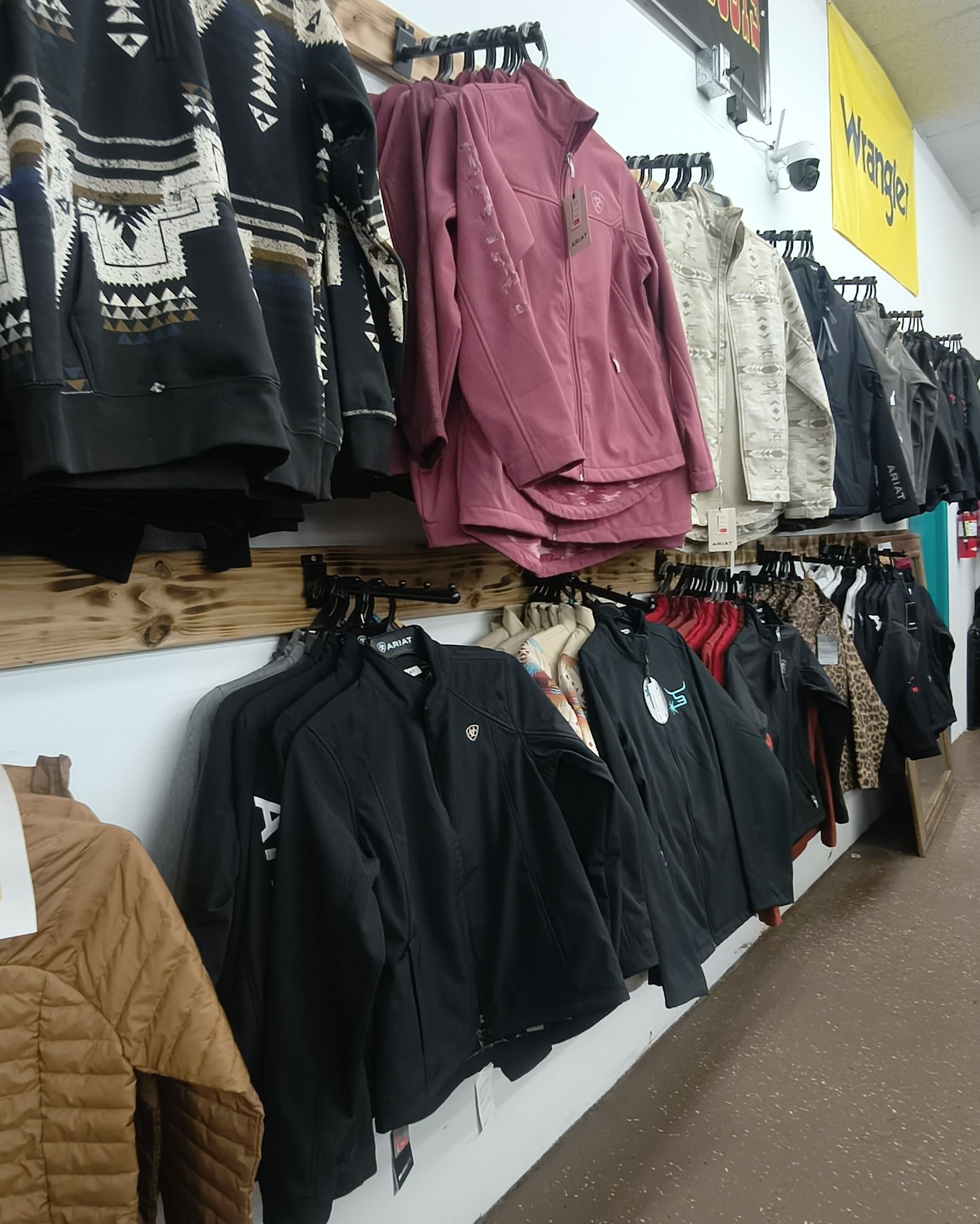 Clothing store display with hanging jackets and sweaters in black, pink, beige, and brown