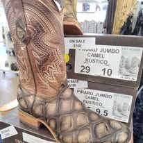 Cowboy boots on display with sale tags, including brown jumbo camel rustic boots.