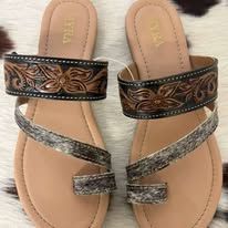Pair of tan sandals with metallic patterned straps on a white furry surface