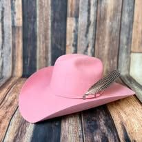 Pink cowboy hat with a feather on a rustic wooden background