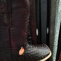 Close-up of a black textured boot next to hanging fabric bags or clothing pieces