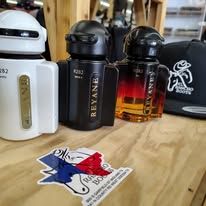 Perfume bottles on a wooden table beside a black bag and sticker with a red-blue horse logo