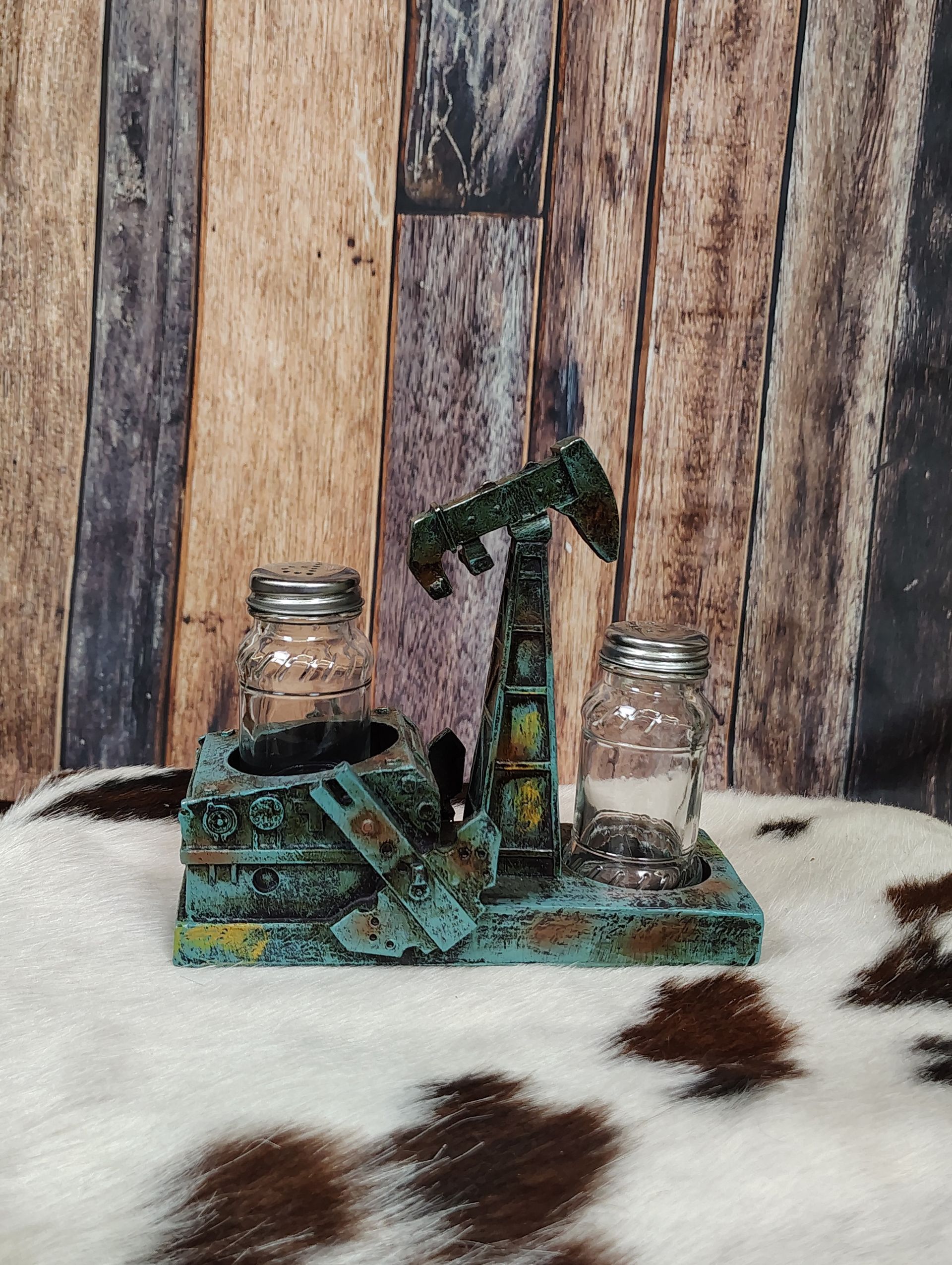 Miniature oil pump scene with two small jars on a rustic wooden and cowhide background