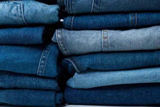 Stacks of folded blue jeans neatly piled on a shelf