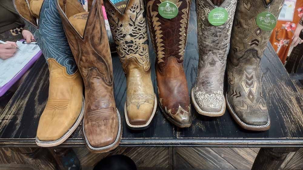 Display of assorted cowboy boots in tan, brown, leopard print, and snakeskin on a store shelf