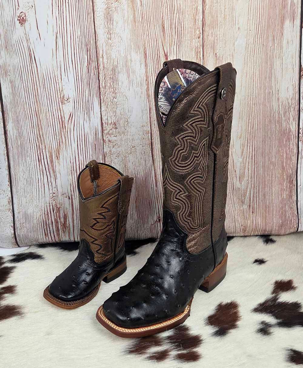 Two western-style boots, black and brown, standing on a spotted rug against a wood backdrop.