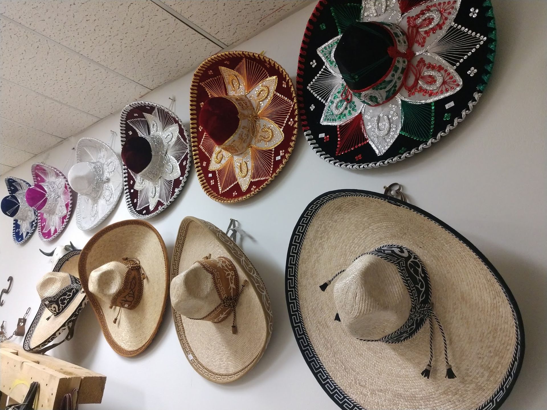 Wall display of colorful sombreros hanging on a wall, including black, red, and straw hats.