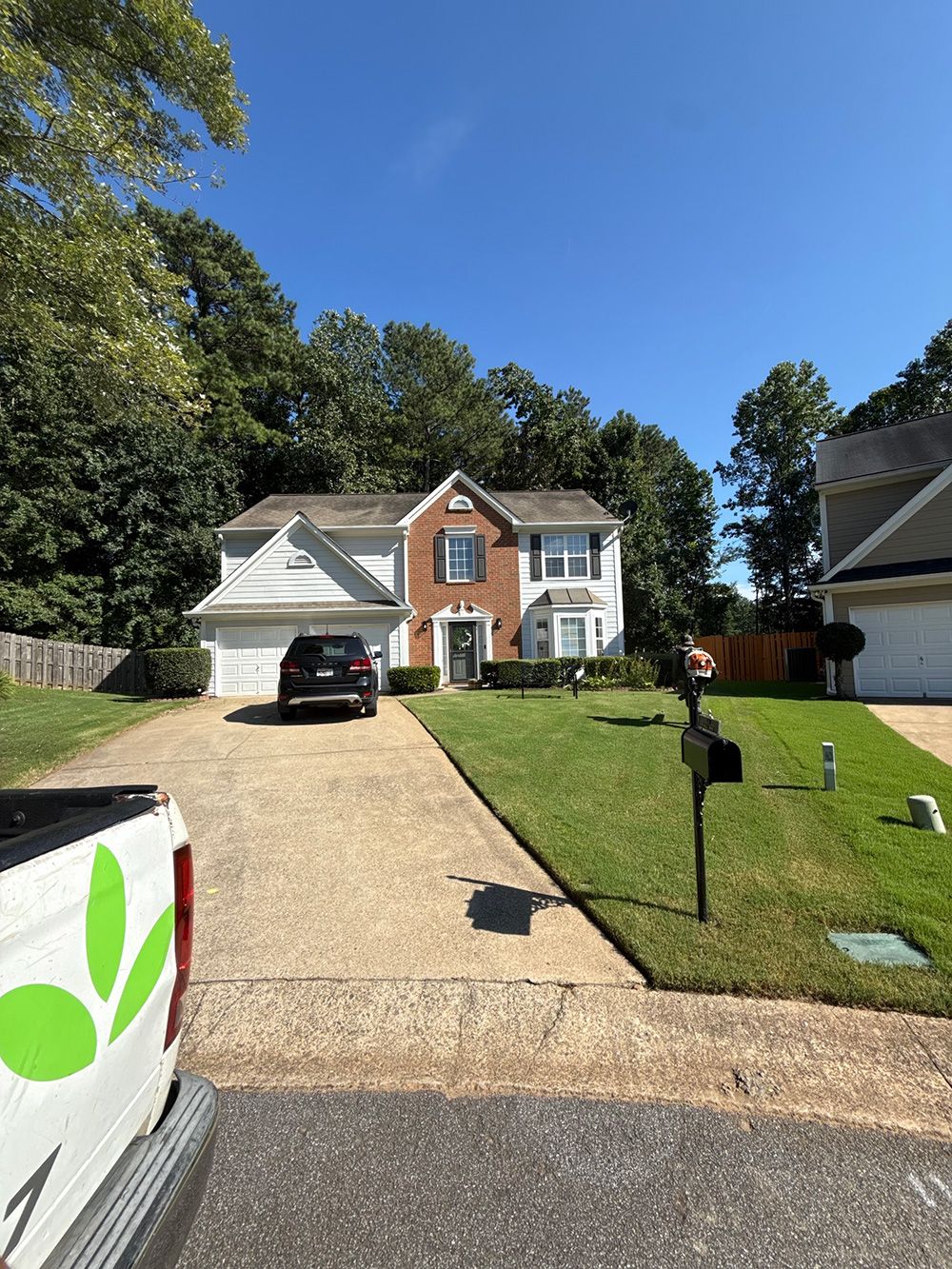 Two-story house with a brick facade and attached garage, on a sunny day. A vehicle is in the driveway.