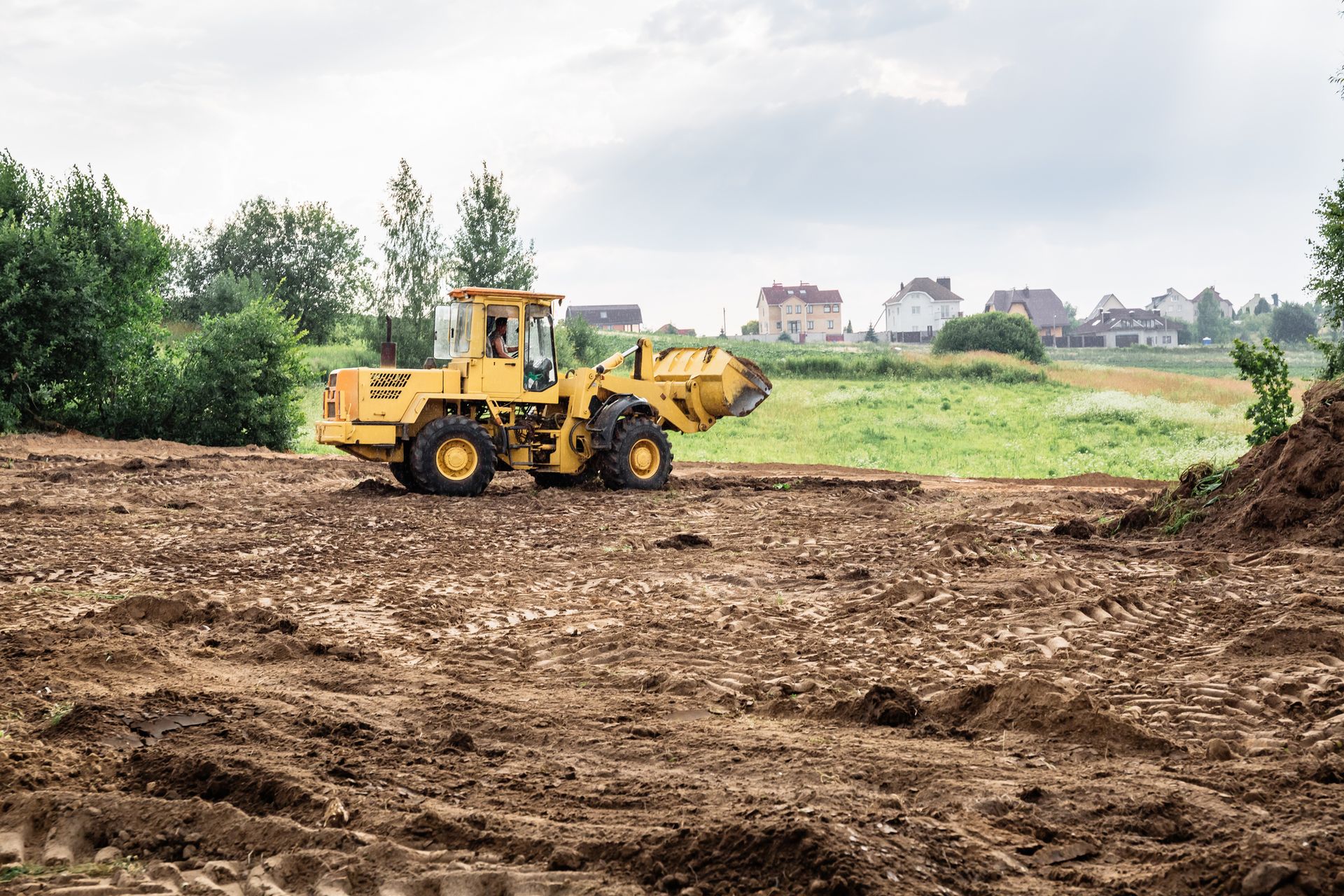 Yellow truck doing land grading and leveling.