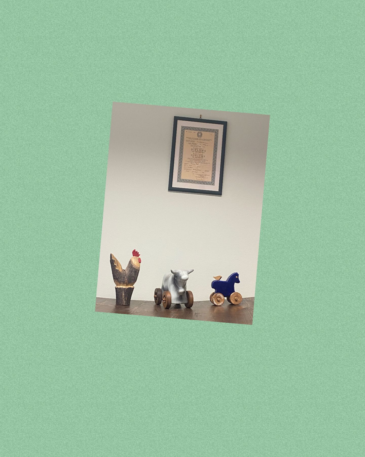 Piccola mensola a muro con tre statuette sotto un quadro incorniciato su una parete verde.